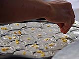 Sprinkling corn kernels onto khanom krok, Sukhmvit near Thonglor, Bangkok