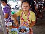Adding slices of red-cooked pork, Sukhothai-style Noodle Shop