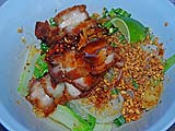Assembled bowl of Sukhothai-style hot and sour noodles with roasted pork belly and lettuce