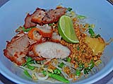 Assembled bowl of Sukhothai-style hot and sour noodles with sliced pork and Chinese broccoli